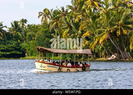 Les passagers d'un petit bateau traversant l'un des nombreux canaux sur les backwaters près de Alleppy et Kumarakom dans le Kerala, en Inde. Banque D'Images