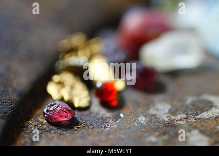 Le grenat almandin rouge profond, pépites d'or, pierre de lune, un rubis rose et un couple de cristaux de Topaze, l'ensemble de la Finlande Banque D'Images