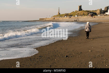 Une femme marchant le long de la plage à Aberystwyth, Pays de Galles, Royaume-Uni Banque D'Images