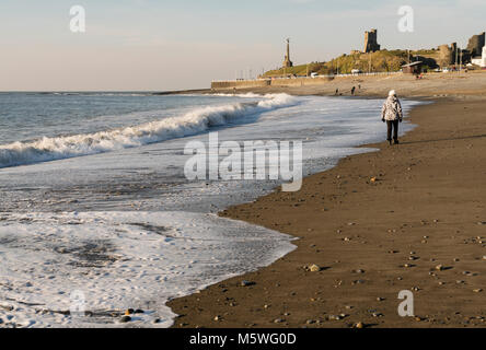 Une femme marchant le long de la plage à Aberystwyth, Pays de Galles, Royaume-Uni Banque D'Images