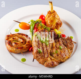 Assiette gastronomique avec côtelettes d'agneau grillées, saucisses en spirale et légumes rôtis servis dans un restaurant de mariage Banque D'Images