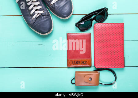 Set de voyage, Passeport, e-book, chaussures, lunettes de soleil, appareil photo. on a wooden surface turquoise, une vue de dessus Banque D'Images