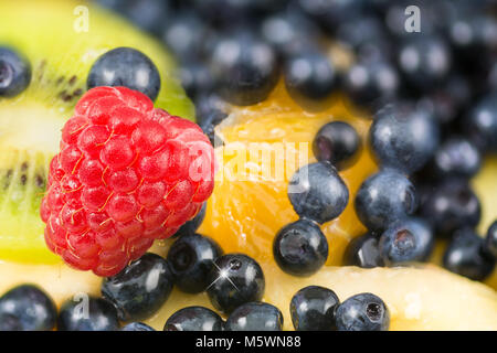 Close-up de belles framboises rouges sur un fond de salade de fruits. La texture colorée du mélange de fruits juteux plein de vitamines. Faible profondeur de shar Banque D'Images