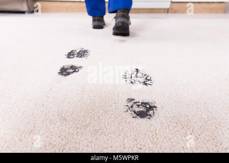 Portrait de personne marchant avec empreinte boueuse sur tapis Banque D'Images