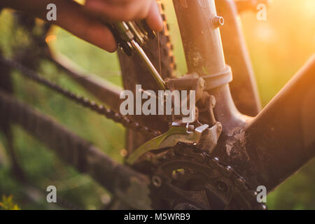 Part avec un vélo d'outil a été engagé dans la fixation d'un vélo en plein air au coucher du soleil close-up Banque D'Images