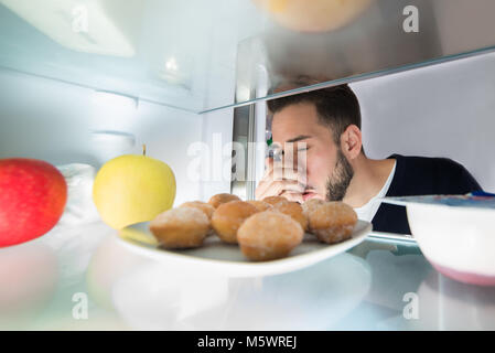 Close-up of a Young Man Holding son nez près de mauvais aliments dans réfrigérateur Banque D'Images