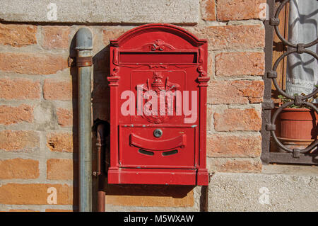 Close-up of a red post box coincé dans un mur de brique dans le coucher du soleil à la ville de Venise, l'historique et étonnante cité marine. Banque D'Images