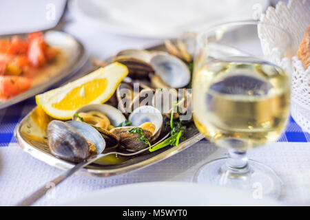 Palourdes servi sur de l'argenterie avec du vin blanc et tomates en salade, Portugal Banque D'Images