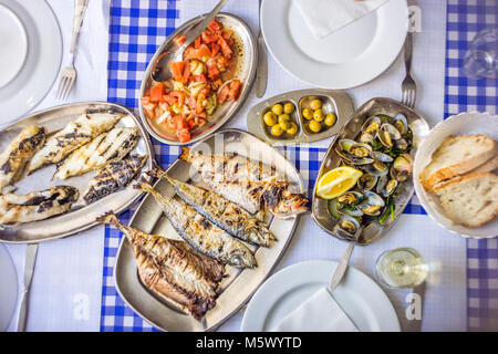 Fête du poisson : loup de mer, Golden, chinchard accompagné de salade de tomates, de palourdes, de pain et de vin blanc, Portugal Banque D'Images