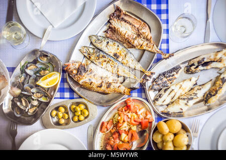 Fête du poisson : loup de mer, Golden, chinchard accompagné de salade de tomates, de palourdes, de pain et de vin blanc, Portugal Banque D'Images