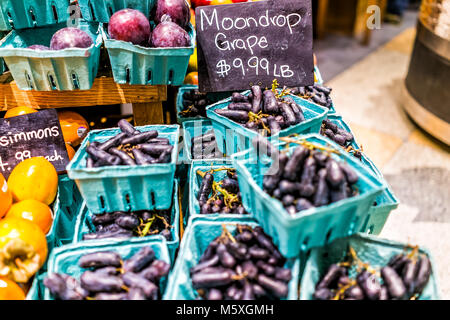 De nombreux gros plan juteux frais purple moon drop moondrop raisin dans les boîtes, les caisses sur l'affichage dans le farmers market sur table en bois par les kakis, signes, : Banque D'Images