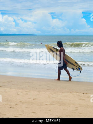 CANGGU, BALI, INDONÉSIE - Jan 19, 2017 : Local surfer walking with surfboard sur la plage. L'île de Bali est l'une des meilleures au monde surf destina Banque D'Images