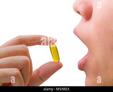 Jeune femme part garder le poisson huile capsule près de bouche ouverte. Femme de prendre des pilules oméga-3. Vitamines et suppléments concept. Banque D'Images