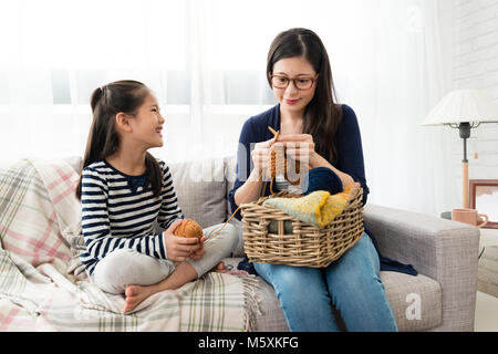 Heureux les enfants d'Asie assis sur le canapé avec sa mère et tricoter ensemble dans la salle de séjour à la maison Banque D'Images