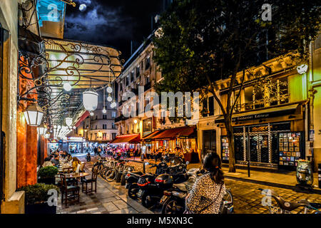 Une touriste promenades le long d'une rue animée dans le Quartier Latin de Paris France avec des cafés, boutiques et restaurants sous la pleine lune Banque D'Images