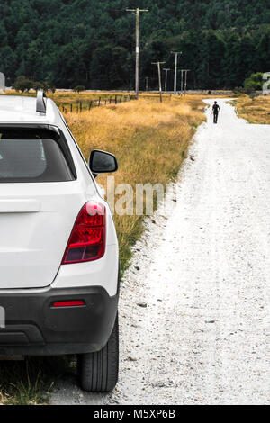 Femme marche loin de voiture en stationnement dans la campagne rurale Banque D'Images