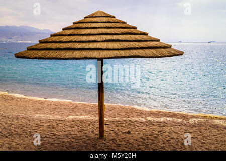 Parasol sur la plage de la Mer Rouge à Eilat, Israël. Jour nuageux après la pluie et hors saison. Thème vacances et voyages. Banque D'Images