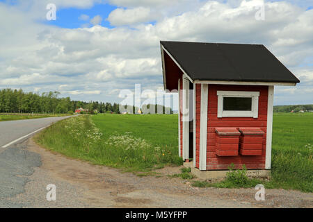 Abribus en bois rouge et deux boîtes de courrier par chemin rural à l'été. Banque D'Images