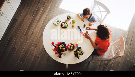 Jeune mère et son fils sont la peinture des oeufs de Pâques Banque D'Images