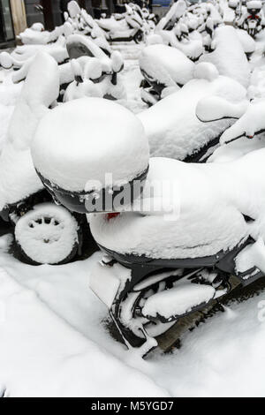 La neige a couvert deux ou trois roues motorisé haut cas garées à l'extérieur dans les rues de Paris lors d'une journée d'hiver. Banque D'Images