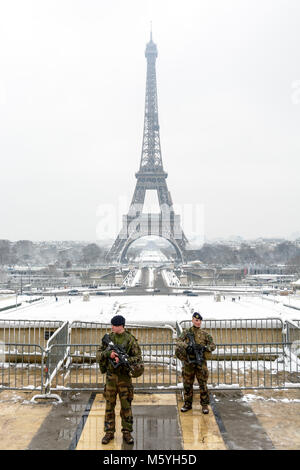 Dans le cadre du plan Vigipirate, deux soldats français patrouille avec fusil d'assaut sur l'esplanade du Trocadéro, en face de la Tour Eiffel, sur un jour de neige. Banque D'Images