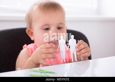 Close-up of a Cute Baby Girl Holding Family Paper Cut Out Banque D'Images