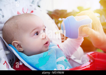 Enfant curieux boit de l'eau de la bouteille. Professionnels et affectifs. Banque D'Images