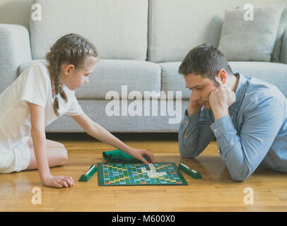 Petite fille et son père jouant au Scrabble jeu de plateau. Banque D'Images