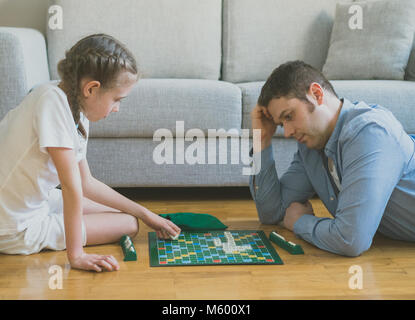 Petite fille et son père jouant au Scrabble jeu de plateau. Banque D'Images