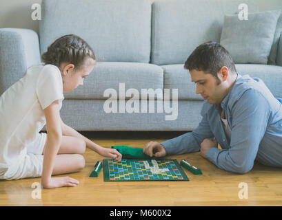 Petite fille et son père jouant au Scrabble jeu de plateau. Banque D'Images