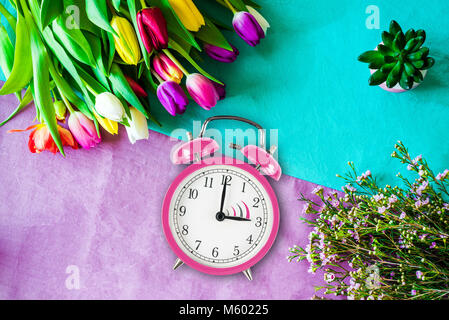 L'heure avancée de rose photo réveil d'en haut comme flatlay avec un bouquet de tulipes et de fleurs en face de l'arrière-plan coloré dans Banque D'Images