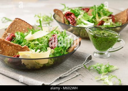 La jeune niçoise Salade de laitue, tomates séchées au soleil, fromage, pain, chips et au pesto Banque D'Images