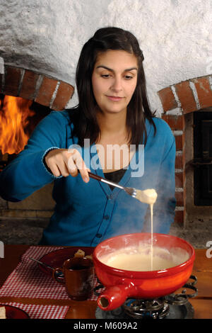 Photo d'une belle femme trempant dans le pain de fromage fondu dans un caquelon. Banque D'Images