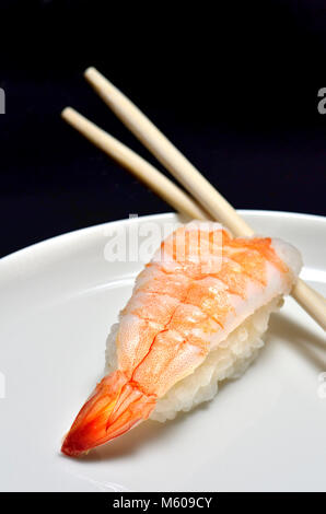 Sushi on a white plate : Nigiri (poisson servi sur le dessus du riz) et baguettes Banque D'Images