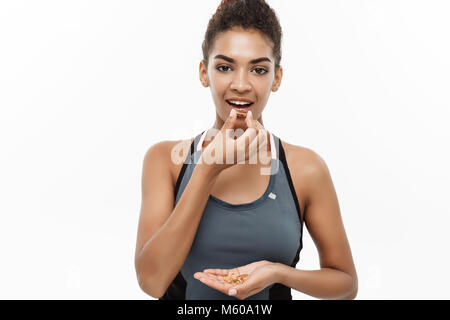 Concept de remise en forme et en bonne santé - Closeup portrait of beautiful African American prendre une pilule d'huile de foie de morue. Isolé sur fond blanc studio. Banque D'Images