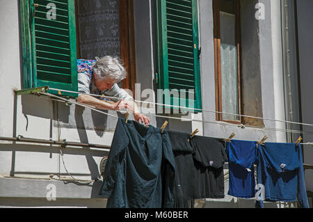 Colle di Val d'Elsa, Italie - 13 mai 2013. Femme âgée enfiler ses vêtements à sécher à fenêtre dans Colle di Val d Elsa. Célèbre pour sa production de cristal. Banque D'Images