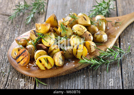 La cuisine végétalienne : pommes grillées au romarin servi sur une planche en bois Banque D'Images