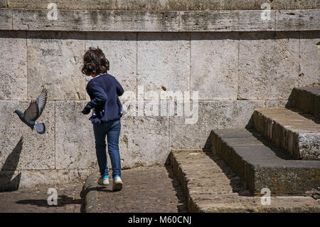 Orvieto, Italie. Vue de little girl Playing with dove près de l'escalier de pierre à Orvieto, une agréable et bien préservé de ville médiévale. Banque D'Images