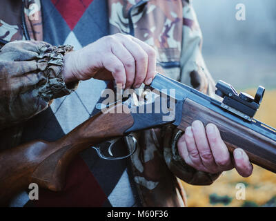 Le tir sportif. Hunter le rechargement cartouche dans champ. La fumée provenant du tronc des fusil de chasse à canon lisse après le tir. Banque D'Images