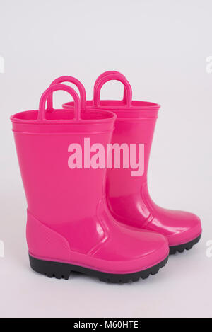 Une paire de bottes de pluie pour enfants rose sur fond blanc. Banque D'Images