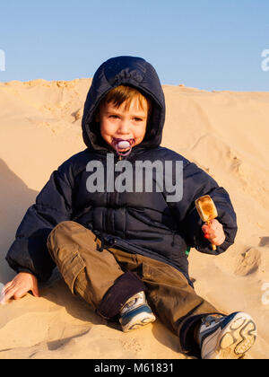 Dans le désert du Sahara, l'enfant joue avec le sable des dunes, en vacances, tourisme Tunisie Douz Banque D'Images