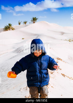 Dans le désert du Sahara, l'enfant joue avec le sable des dunes, en vacances, tourisme Tunisie Douz Banque D'Images