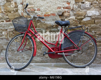 La femme rouge vélo contre un mur de briques Banque D'Images