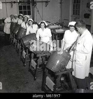 Années 1950, historiques, enseignant dans une laiterie montrant un groupe d'apprenants de sexe féminin ou des apprentis comment utiliser le mini bidons pour faire buttter. En Grande-Bretagne, avant et après la Seconde Guerre mondiale, il était nécessaire de produire plus d'aliments cultivés sur place et d'enourage plus jeunes à entrer dans le secteur de l'agriculture et de l'aquaculture. Banque D'Images