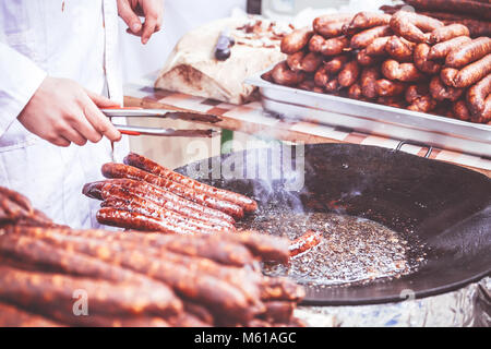 Saucisse fumée maison frit dans la graisse dans un marché de rue, selective focus et petite profondeur de champ. Banque D'Images