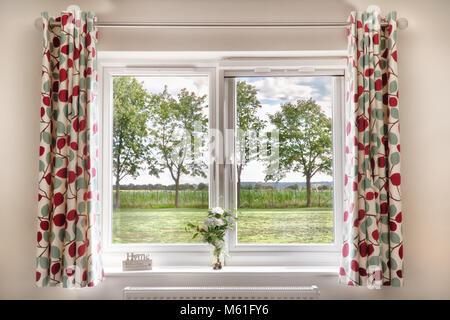 Fenêtre avec vue sur champs et d'arbres en milieu rural. Les rideaux et un bel été en font une belle scène et une place quelqu'lo Banque D'Images