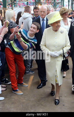 Un jeune homme de faire un trys avec selfies Britain's La reine Elizabeth II comme elle tours Marché St Georges à Belfast, le mardi 24 juin 2014. La Reine est sur une 3 journée de visite de l'Irlande du Nord. Piscine Photo/Paul McErlane Banque D'Images