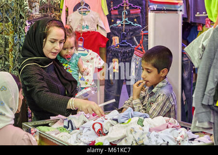 Kashan, Iran - avril 25, 2017 : femme iranienne avec deux enfants choisit les vêtements pour enfants sur le marché de l'Est. Banque D'Images