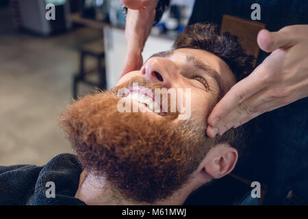 Jeune homme barbu souriant pendant un massage relaxant temple Banque D'Images