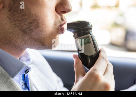 Close-up d'un jeune homme assis à l'intérieur car la prise d'alcool Test Banque D'Images